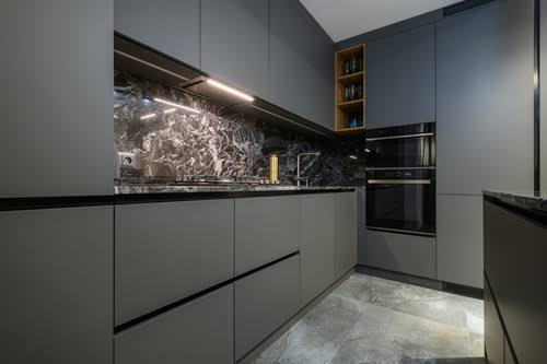 Modern handleless kitchen cabinetry with LED task lighting and marble wall panels