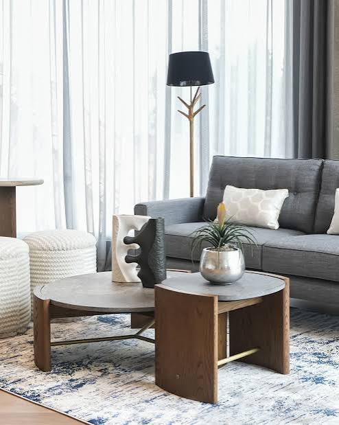 Contemporary dark grey couch styled with round wooden nesting coffee tables