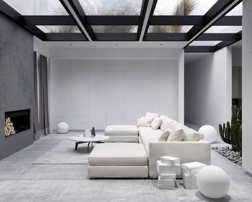 Large modern white sectional couch in an architectural living room with skylights